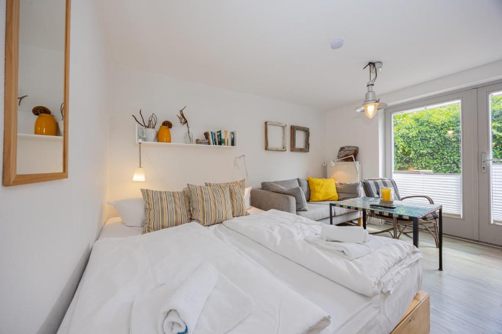 a white bedroom with a large bed and a living room at Stabenweg Whg. 1 in Göhren