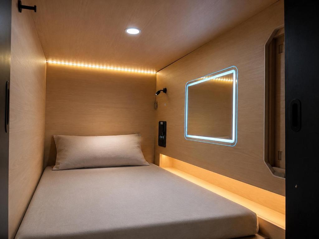 a small bed in a small room with a window at OWNLY CAPSULE Hotel in Bangkok