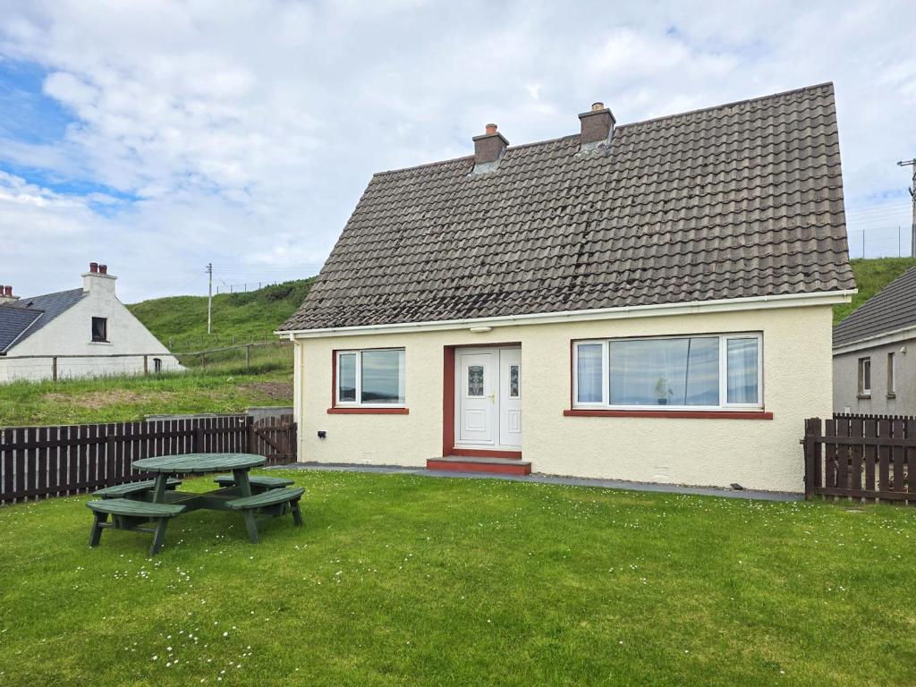 a small house with a picnic table in the yard at Mo Dhachaidh in Gairloch