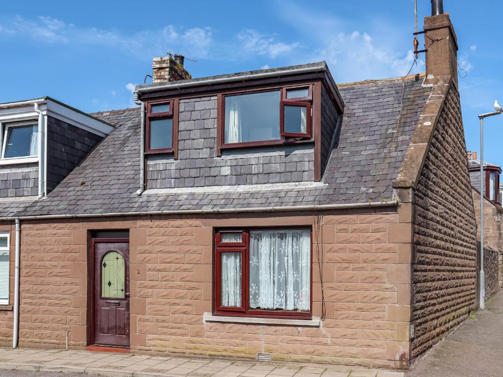 a brick house with red windows and a gray roof at Weaver's Cottage in Banchory