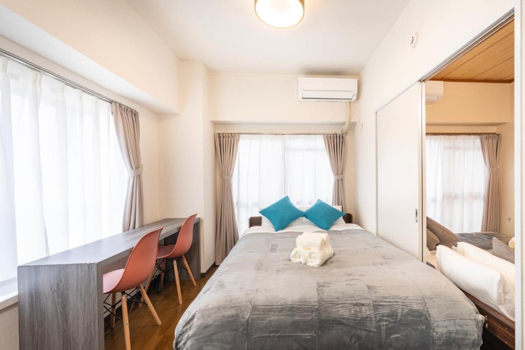 a bedroom with a bed and a desk and some windows at CS Residence Chiba in Chiba