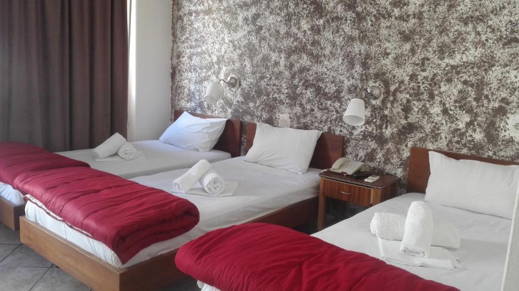 una camera d'albergo con due letti con lenzuola rosse di Hotel Ionion a Pireo