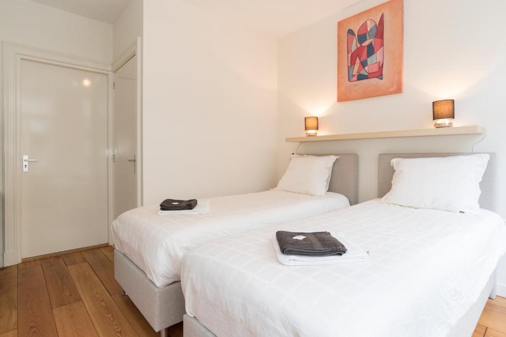 アムステルダムにあるOld / New Pijpの白い壁とウッドフロアの客室で、ベッド2台が備わります。