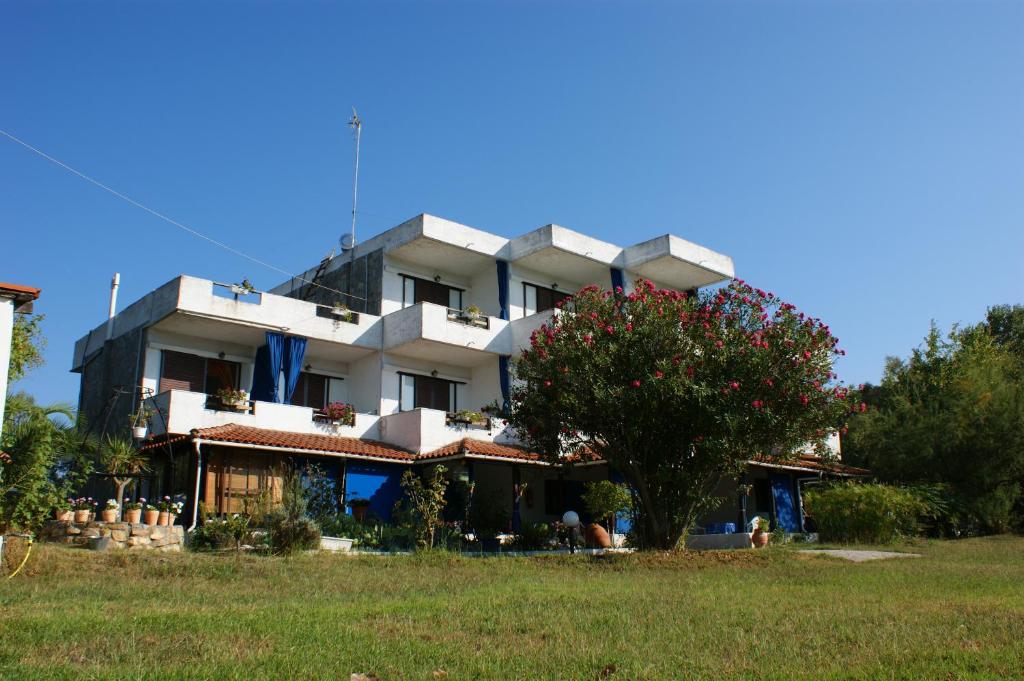 duży biały budynek z drzewem przed nim w obiekcie Villa Iris Studios w mieście Ormos Panagias