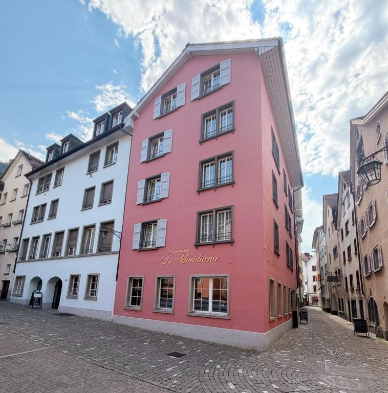 a pink building in the middle of a street at Hotel Alpenstadt in Chur