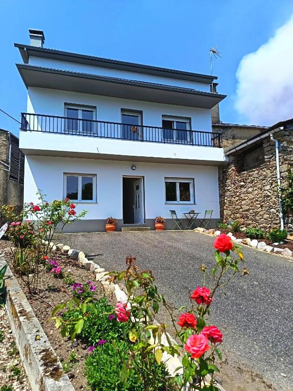 ein weißes Haus mit Blumen davor in der Unterkunft A Esteva in Orol