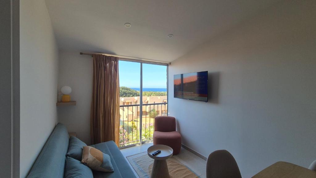 a living room with a couch and a large window at Between Calvi and Ile Rousse seaside in Lumio