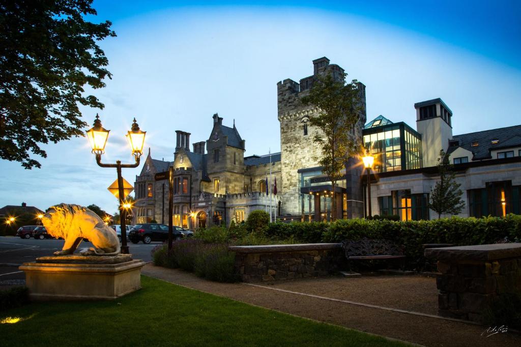 un grande edificio con una statua di leone davanti di Clontarf Castle Hotel a Dublino