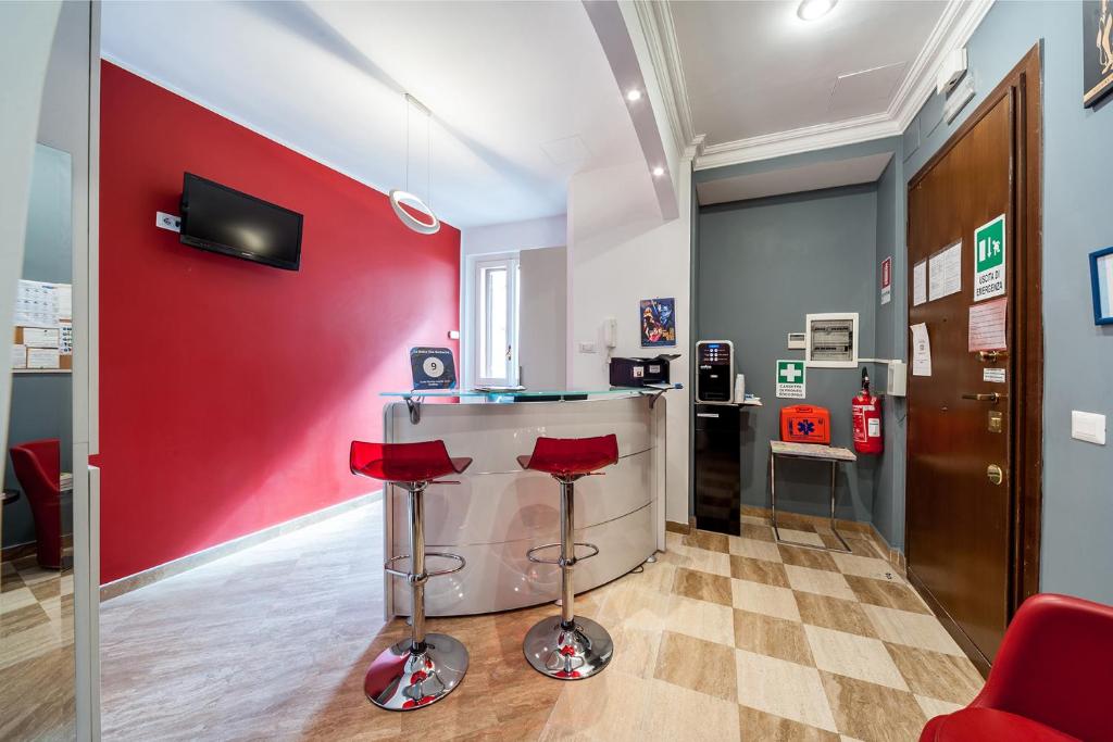 a bar in a room with red walls and stools at La Dolce Vita Barberini in Rome