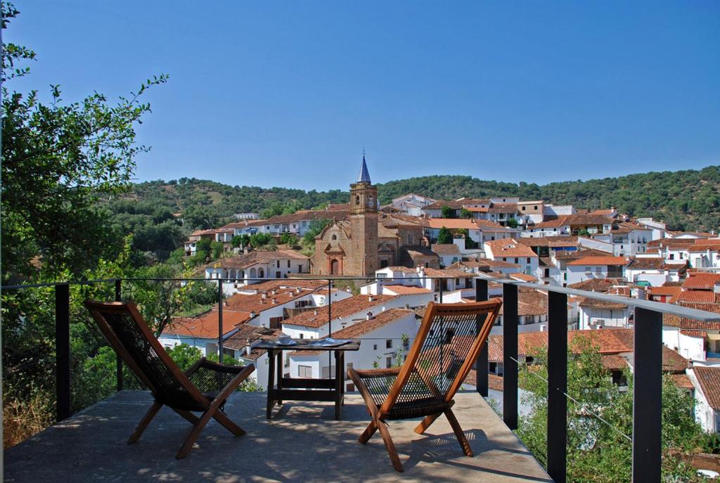 ein Balkon mit zwei Stühlen und einem Tisch und einer Stadt in der Unterkunft El Risco del Lomero, chimenea 4 Huesp max in Valdelarco