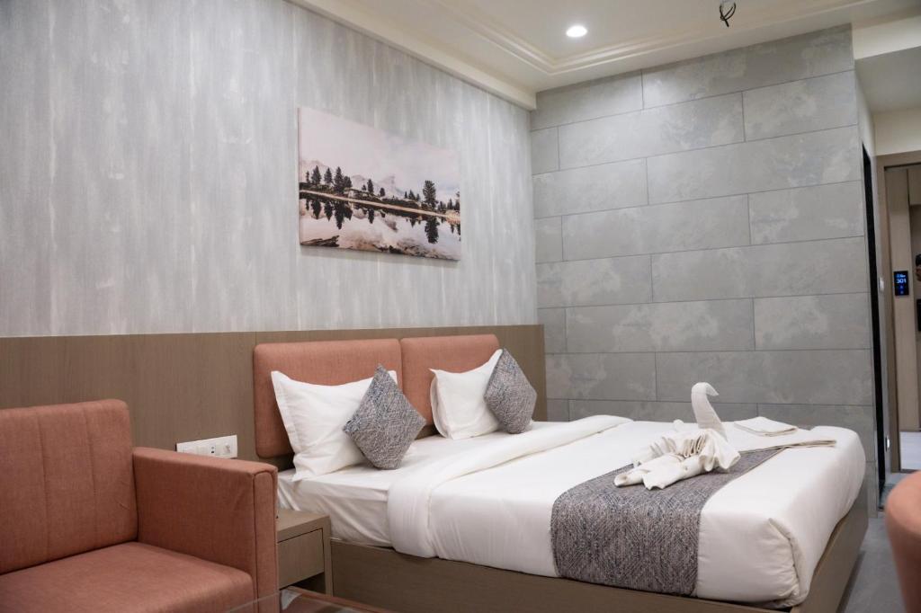 a hotel room with a bed and a chair at Hotel Emirest in Bhilad