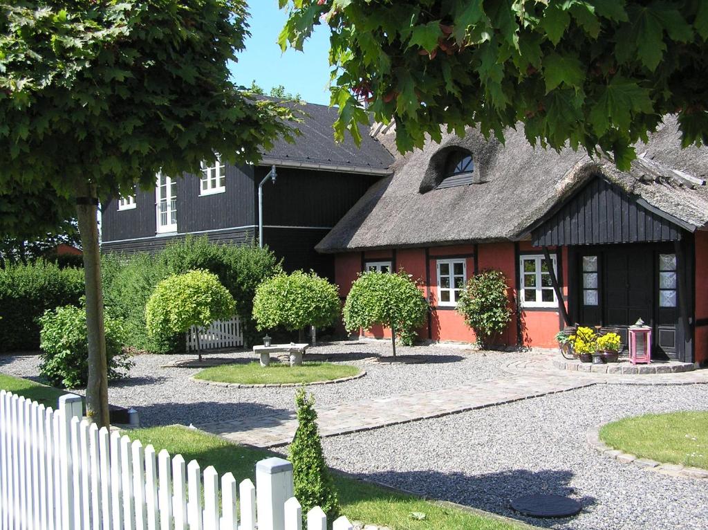 una casa con una cerca blanca delante de ella en Lolland Bed & Breakfast en Søllested