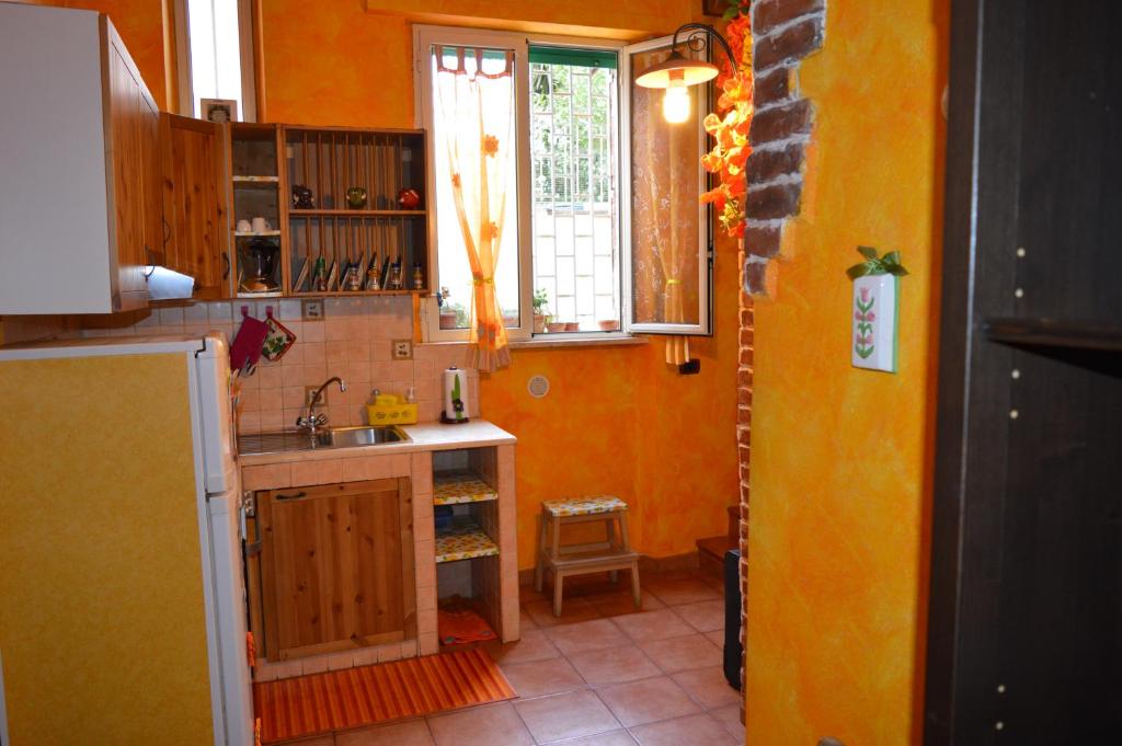 ローマにあるLa Casetta Gialla di Edoardoのオレンジ色の壁のキッチン、シンク、窓が備わります。