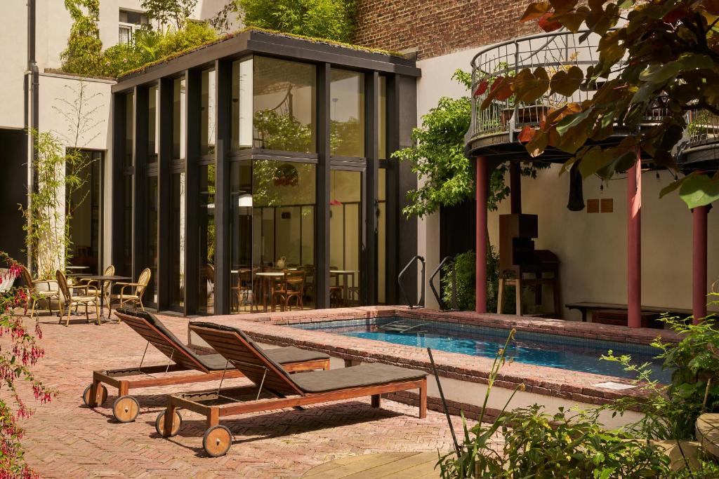 ein Swimmingpool mit zwei Liegestühlen neben einem Haus in der Unterkunft Le Berger Latroupe Hotel in Brüssel
