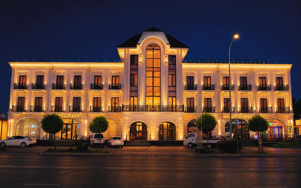 a large white building with cars parked in front of it at Amanat Prestige Hotel in Samarkand