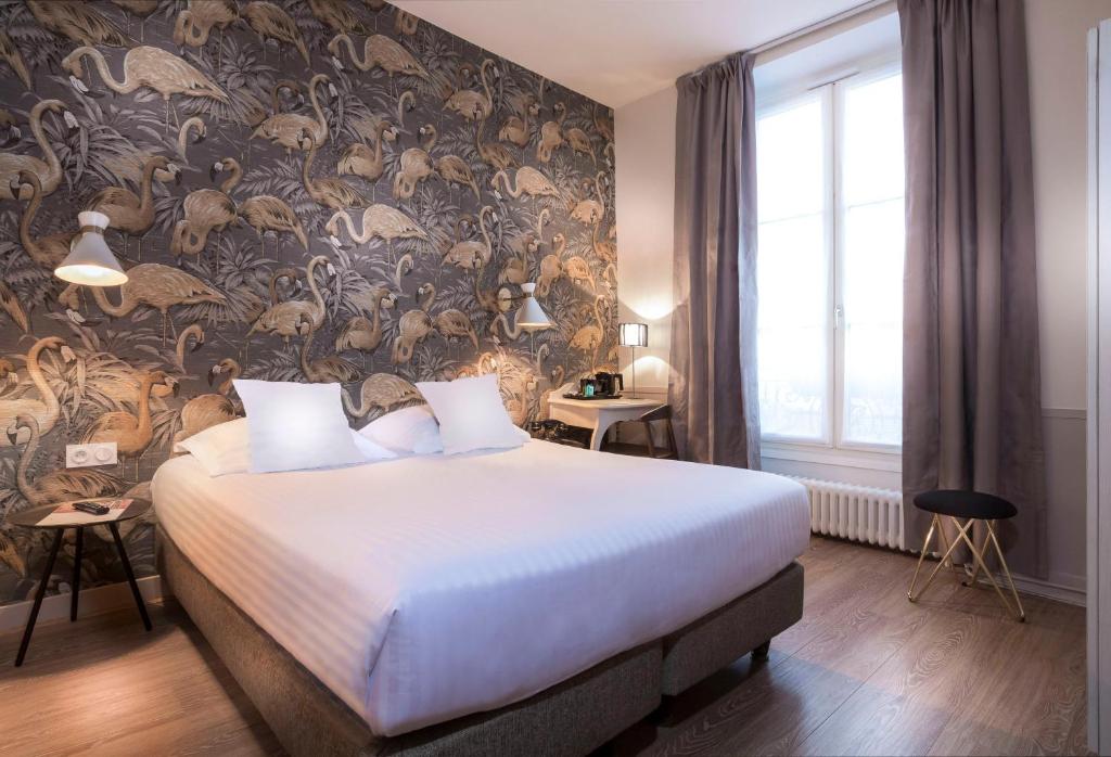 1 dormitorio con 1 cama grande y papel pintado con motivos florales en Hôtel Jeanne d'Arc Le Marais en París