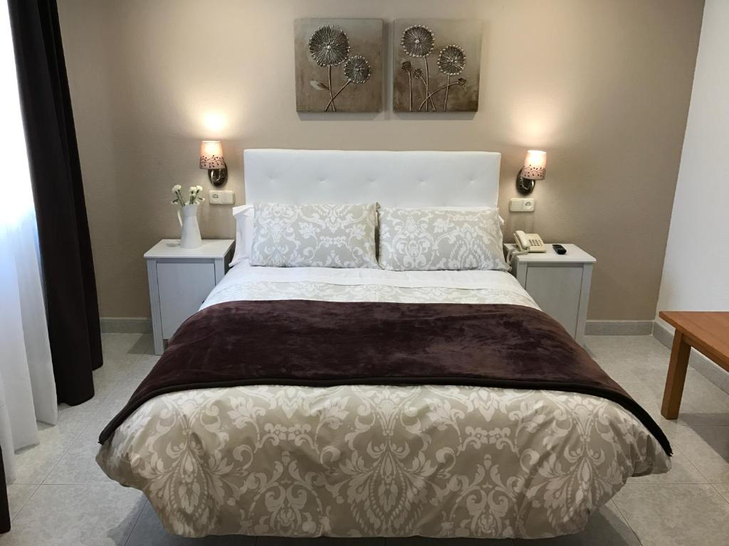 1 dormitorio con 1 cama blanca grande y 2 mesas en Hostal Alcázar, en Toledo