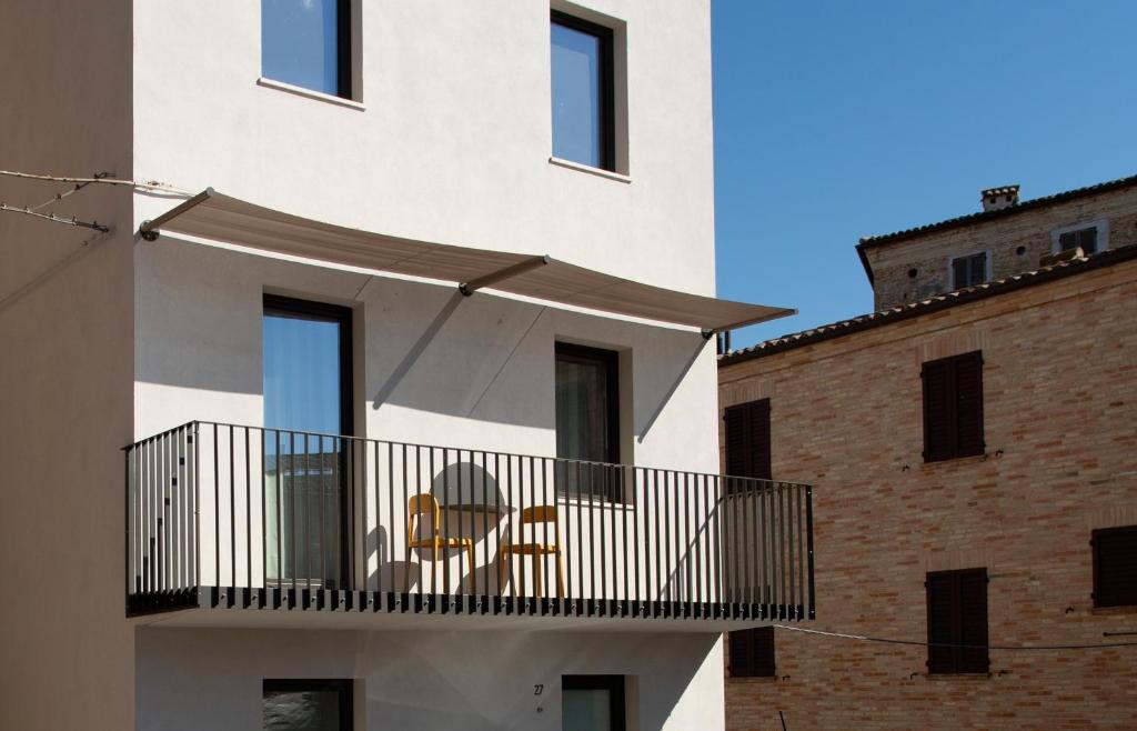 a white building with a balcony with a table and chairs at Duesette Rooms in Filottrano