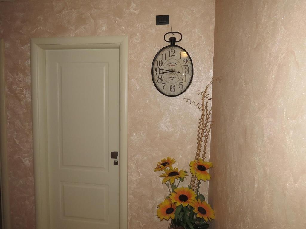 a clock hanging on a wall next to a door at B&B La Maison in Potenza