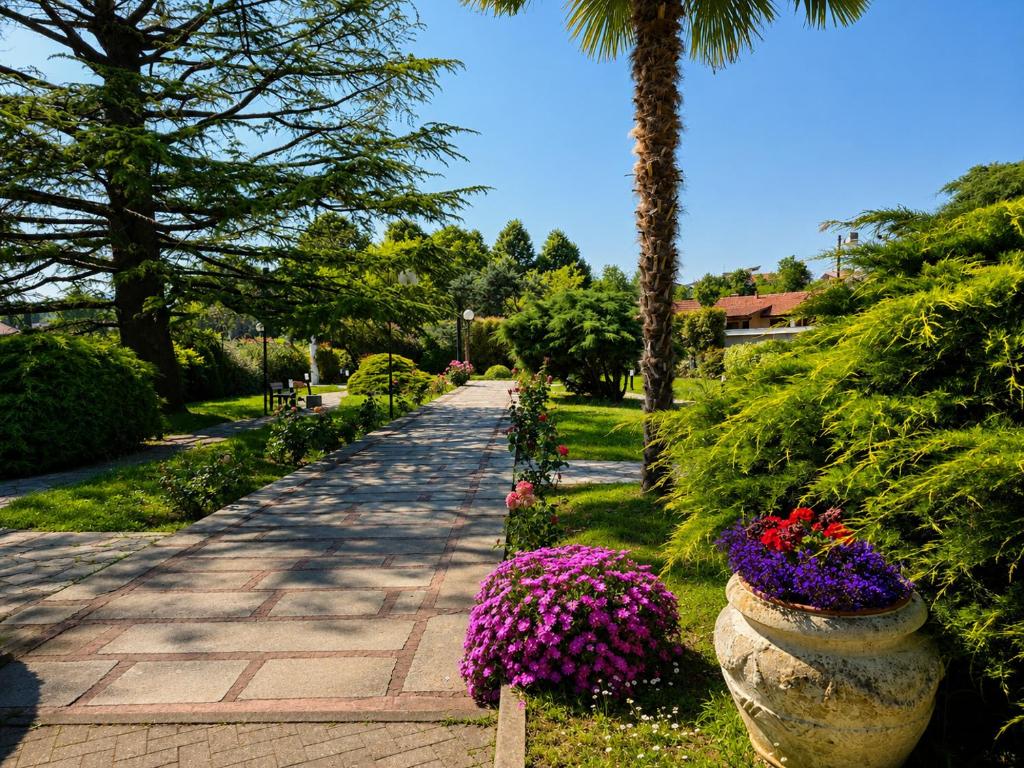 ein mit Blumen gesäumter Gehweg in einem Park mit einer Palme in der Unterkunft Phi Hotel Homy Druento in Druento