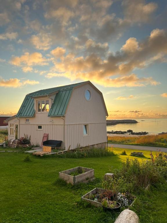 a white barn with a green roof on a field at NEW house by the beach in Andøya