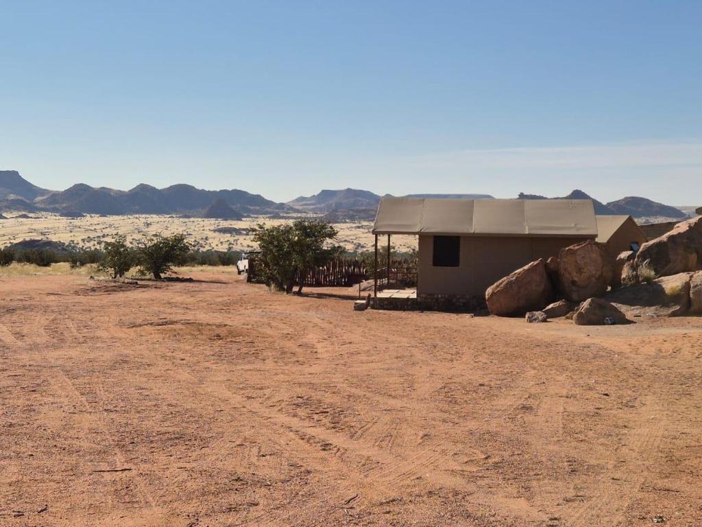 a building in the middle of a desert with mountains at Sky and Stone Tented Camps in Twyfelfontein
