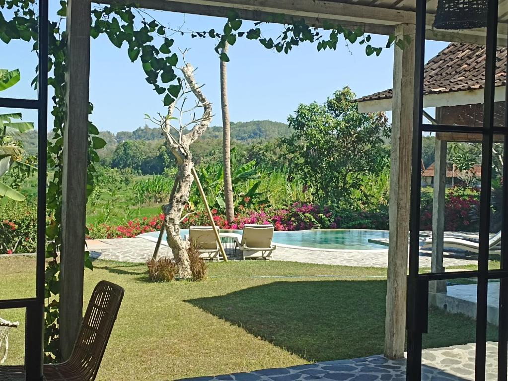a yard with a swing and a swimming pool at Villa With Stunning Paddy Field Views - Kasongan Yogyakarta in Jarakan