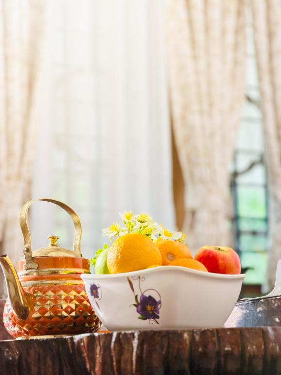 a bowl of fruit and a tea kettle on a table at Mist & Meadows Premium VIlla By STAYVA in Munnar