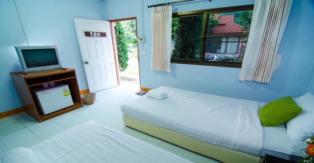 a bedroom with a bed and a tv and a window at Pingdoi Resort in Ban Dong Ma Tun