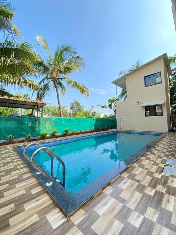 a swimming pool in front of a house at Beach Walk - By Blue waves in Alībāg