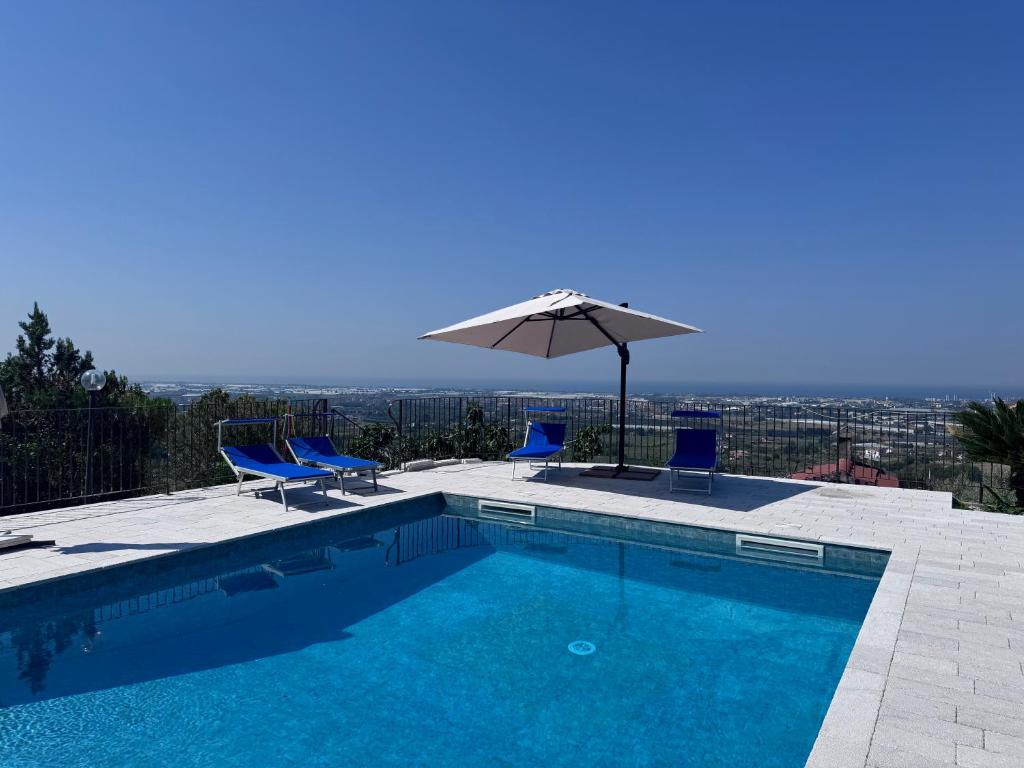 a swimming pool with two chairs and an umbrella at Panora Hill BnB in Faiano