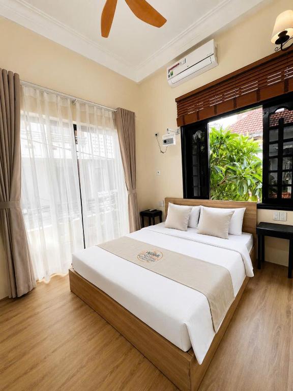a bedroom with a large white bed with a window at Hue Ancient Hostel in Hue