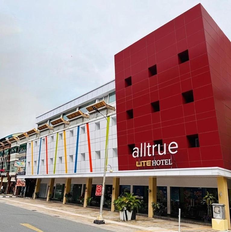 a red building on the side of a street at Alltrue Lite Hotel Nagoya Hill Batam in Nagoya