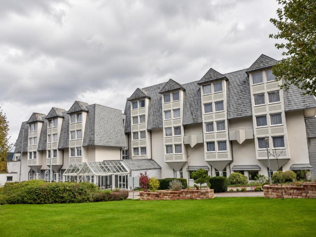 a row of apartment buildings with a green lawn at Sunday Hotel Wiesbaden Niedernhausen Apartments in Niedernhausen