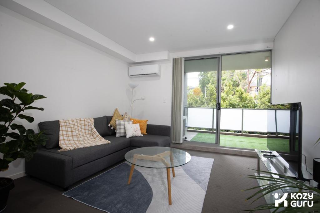 a living room with a couch and a glass table at KozyGuru | Epping | Stylish 1 Bedroom Apartment in Epping