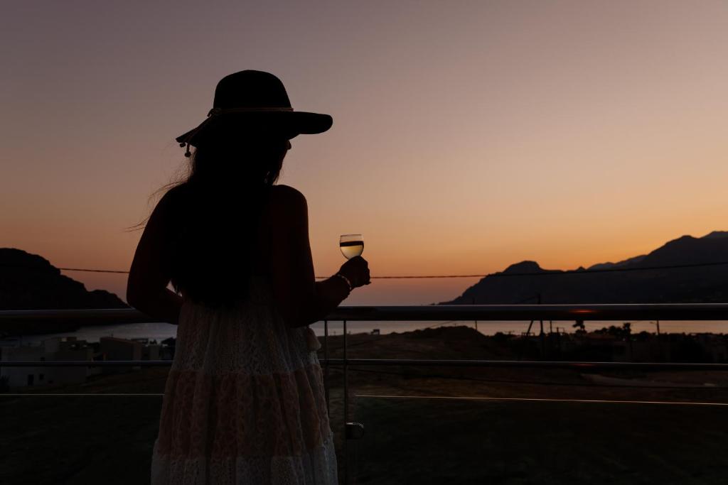 a woman holding a wine glass in front of the sunset at Lamon Villa in Plakias