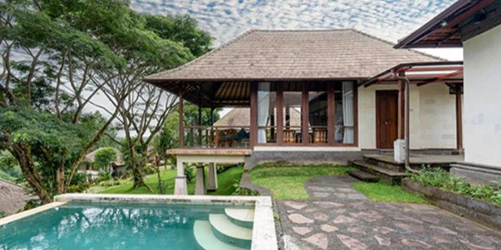 a house with a swimming pool in front of a house at Moksha Wellness Bali in Plaga