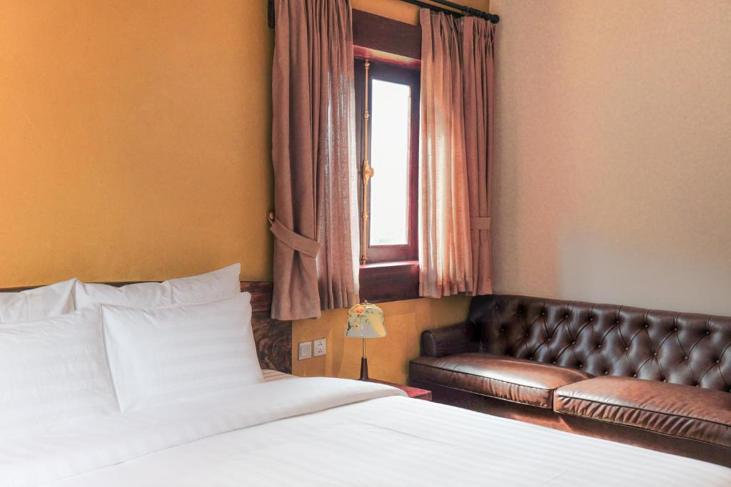 a bedroom with a bed and a leather couch at ALy's Sapa in Tả Van