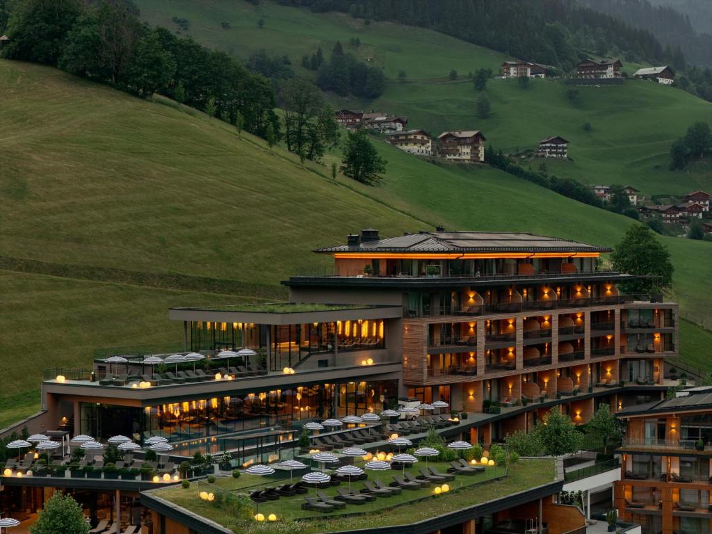 a large building with tables and umbrellas at DAS EDELWEISS - Salzburg Mountain Resort in Grossarl