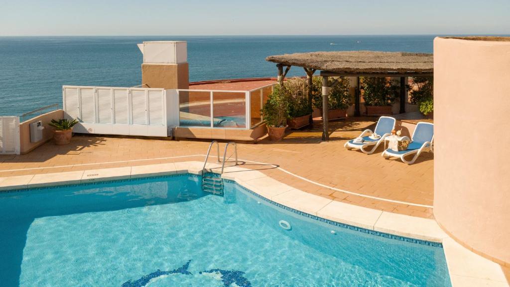 ein Schwimmbad mit Liegestühlen und einem Pavillon und das Meer in der Unterkunft Ona Princesa Playa in Marbella