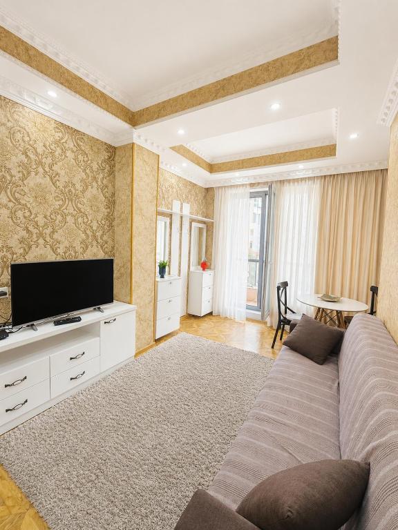 a living room with a couch and a flat screen tv at Historic Centre Apartment Kutaisi in Kutaisi