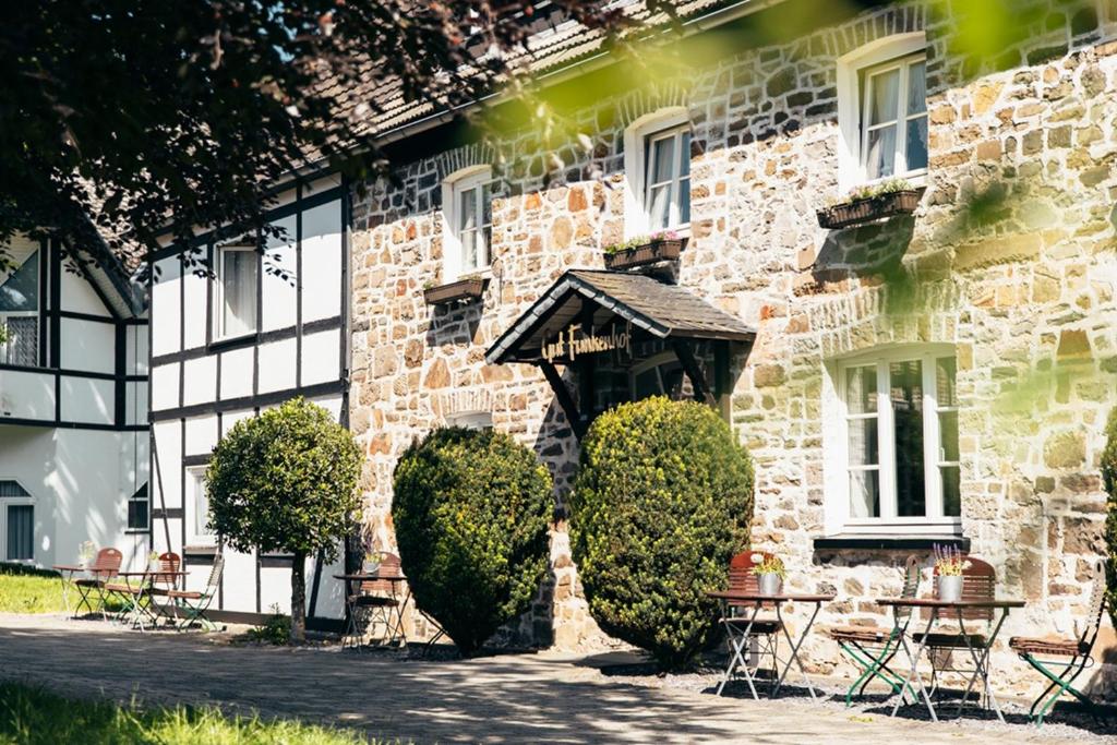 a building with tables and chairs in front of it at Hotel Gut Funkenhof in Sundern