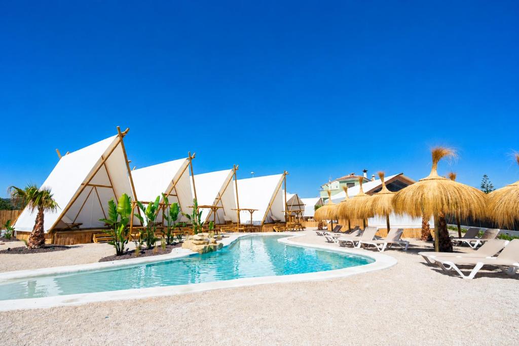 a resort with a swimming pool and straw umbrellas at Kampaoh Kikopark Playa in Oliva
