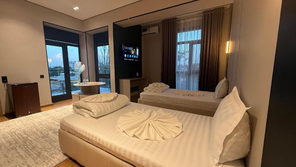 a hotel room with two beds and a balcony at Maskan Premium Hotel Tashkent in Aktepa-Chigatay
