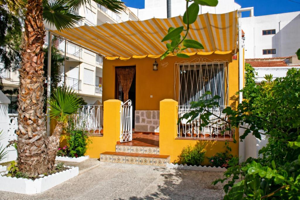 a yellow house with a door and a tree at Casa Galisa in Torrevieja