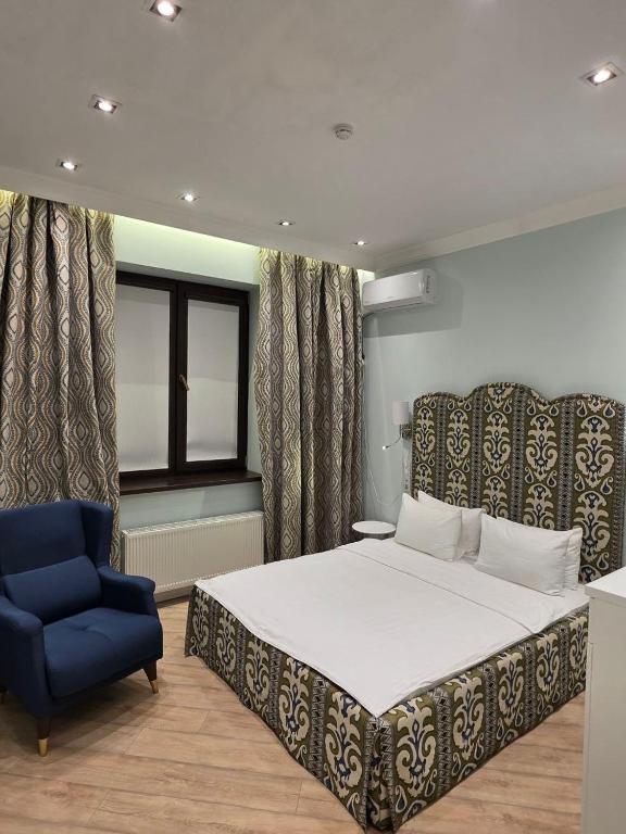 a bedroom with a bed and a blue chair at Njala Residence in Stantsiya Tekeli