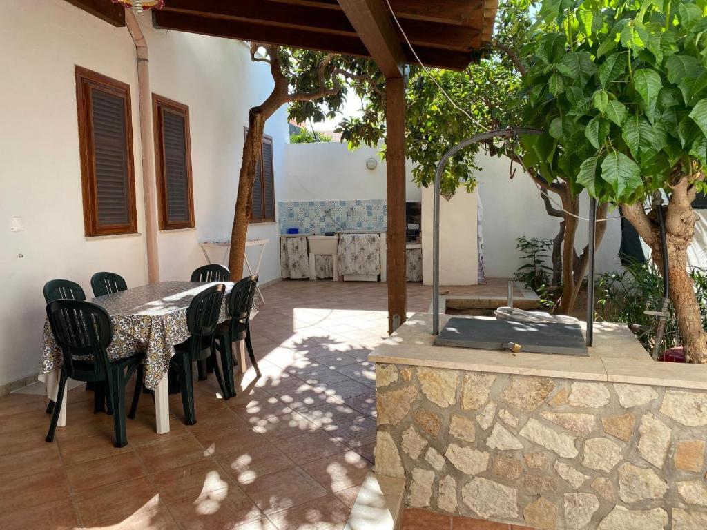a patio with a table and chairs and trees at Casa Nespolo in San Vito lo Capo