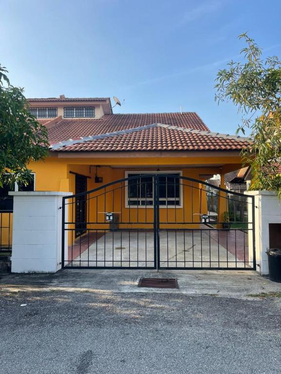 a yellow house with a gate in front of it at FAs KLIA Guesthouse, 4BR 4 AC , NEAR KLIA, NILAI in Sepang