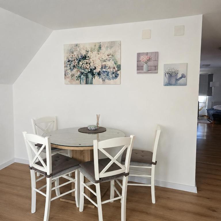 a dining room table with four chairs and a painting on the wall at Apartman Čardak in Gospić
