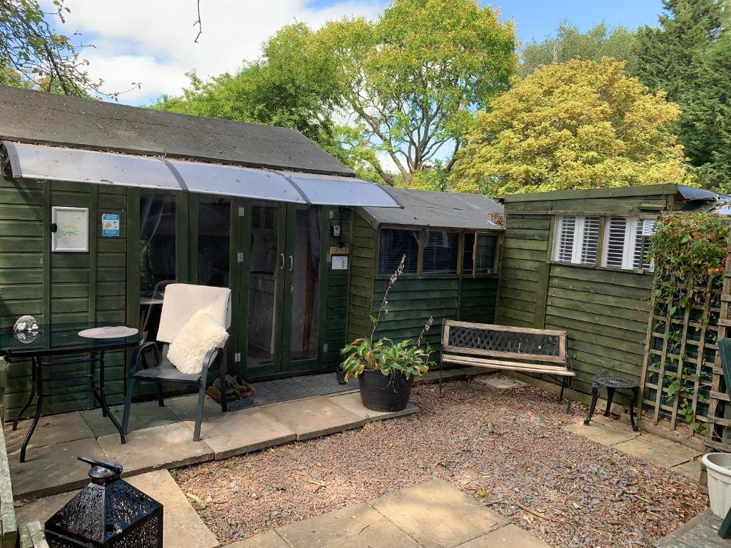 a green house with a bench and a table at Hedgehog Lodge in Colwall